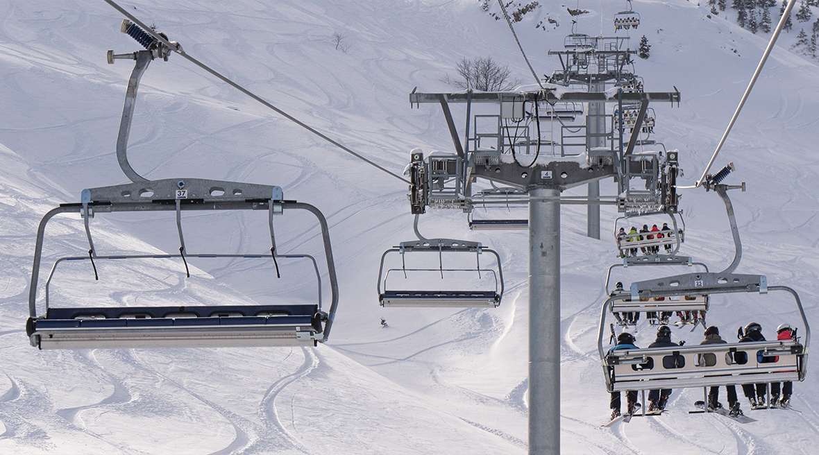 ski lift with skiers riding up the snowy mountain